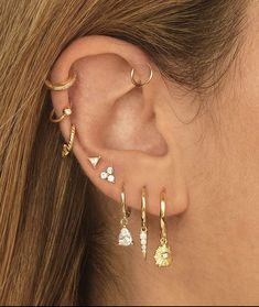 a close up of a person's ear with different types of earrings on it