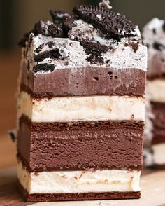 two pieces of chocolate and white cake on a wooden table with one slice cut out