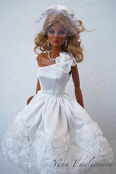 a barbie doll wearing a white dress and veil with flowers on it's head