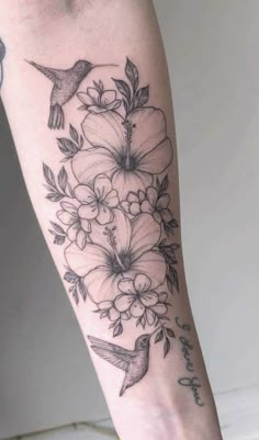 a woman's leg with flowers and birds on it, while she has her arm tattooed