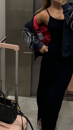 a woman is standing next to her luggage and talking on the phone while wearing a mask