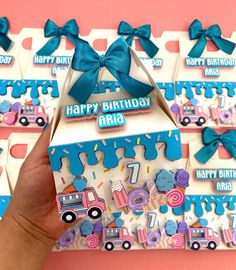 a hand holding up a birthday card in front of some boxes with decorations on them