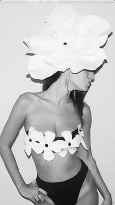 a woman in a bathing suit with paper flowers on her head and one hand on her hip