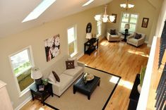 an aerial view of a living room with hardwood floors and white furniture, including couches