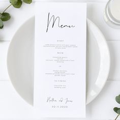 a white plate topped with a menu next to a glass of milk and greenery