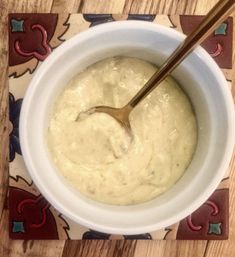 a white bowl filled with batter sitting on top of a wooden table next to a spoon