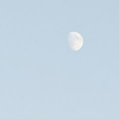 an airplane flying in the sky with a half moon behind it's back end