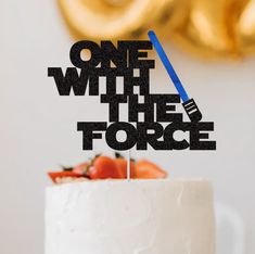 a white cake topped with a star wars inspired topper and a blue light saber