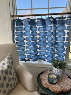 a living room with a chair, table and blue curtains in the window sill