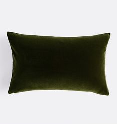 a dark green velvet pillow on a white background