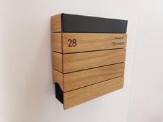 a wooden wall mounted mailbox with the number 28 engraved on it's side