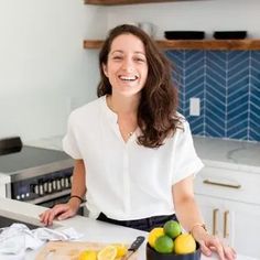 a woman standing in front of a cutting board with lemons and limes on it