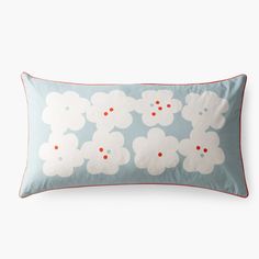 a blue and white pillow with red trim on the bottom that has flowers printed on it