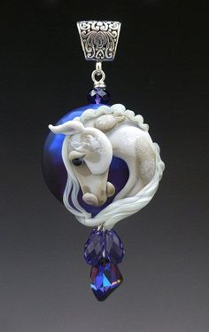 a blue and white necklace with a horse on it's back hanging from a chain