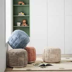 two round poufles sitting on top of a rug in front of a bookshelf