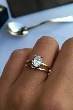 a woman's hand with two gold rings and a diamond ring on top of her finger