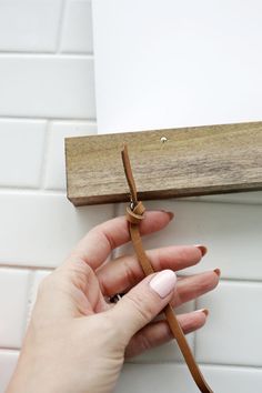 a woman's hand holding onto a piece of wood with a knot on it