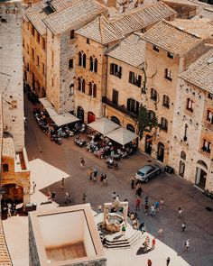 an aerial view of people walking around in the old town square, with cars parked on the street