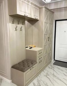 an empty room with white cabinets and grey bench cushions on the bottom, and two doors to the other side