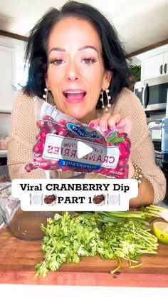 a woman holding up a bag of cranberry dips on top of a cutting board