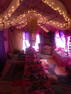 a long table covered in lots of plates and bowls with lights hanging from the ceiling