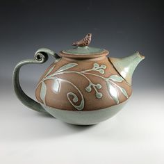 a ceramic teapot with a bird on top