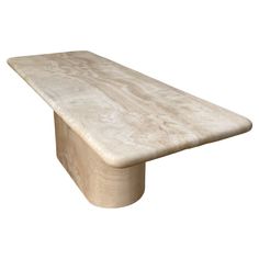 a white marble table sitting on top of a wooden base with no one around it