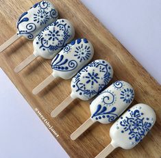 four blue and white cake pops sitting on top of a wooden cutting board