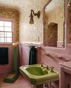 a bathroom with pink walls and green sink in the corner, along with wallpaper