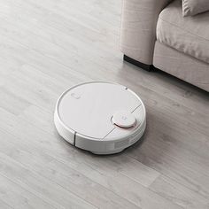 a roomba that is on the floor next to a couch