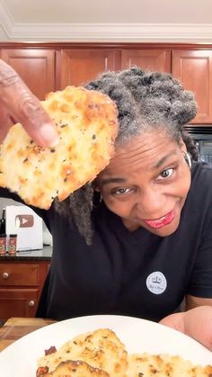 a woman holding up a piece of pizza on top of a white plate in front of her face