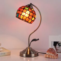 a lamp that is on top of a table next to a book and seashell