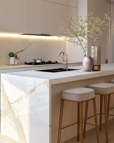 a kitchen with marble counter tops and stools next to an island in the middle