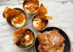 four small bowls filled with food on top of a marble countertop next to another bowl full of food