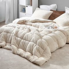 an unmade bed with white pillows and blankets on top of it in a bedroom