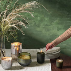 A cozy scene with candles, greenery, and a hand lighting one of the candles. Cedar Candle, Cedar Box, Holiday Fragrance, Pink Candles, Free Plants, Simple Holidays, Crackle Glass, Tin Candles, Glass Holders