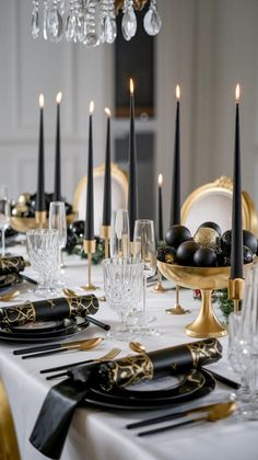 the table is set with black and gold place settings, silverware, and candles