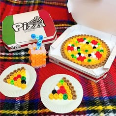 the pizza is made out of legos and sits next to two plates with cookies on them