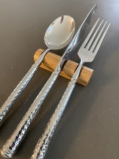 a fork, spoon and knife are sitting on a wooden holder with silverware in it