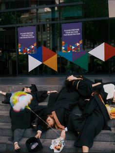 two women in graduation gowns laying on the steps