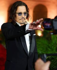 a man in a tuxedo taking a photo with his cell phone while wearing sunglasses