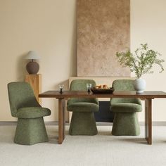 a dining room table with green chairs and a vase on the table next to it