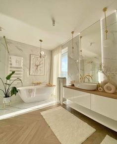 a bathroom with a tub, sink and large mirror