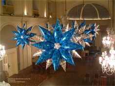 a large blue and white snowflake hanging from the ceiling in a room with chandeliers