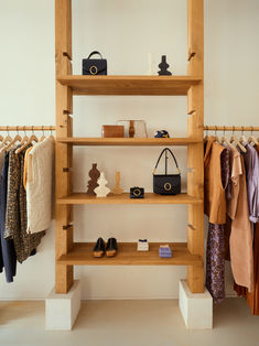 a wooden shelf filled with clothes and handbags