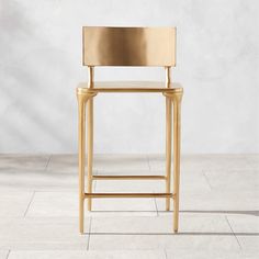 a gold colored chair sitting on top of a tile floor next to a white wall