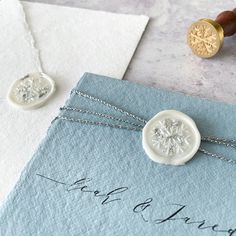 two wax stamp necklaces sitting on top of an envelope