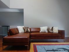 a brown leather couch sitting on top of a hard wood floor next to a rug