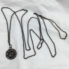 three different necklaces are laying on a white sheet and one has a black medallion