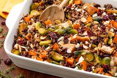 a casserole dish with carrots, brussel sprouts and nuts